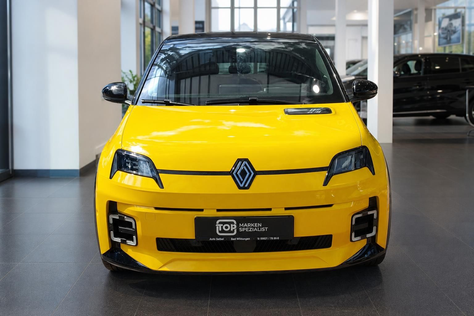 Gelber Renault 5 Frontansicht im Autohaus Showroom