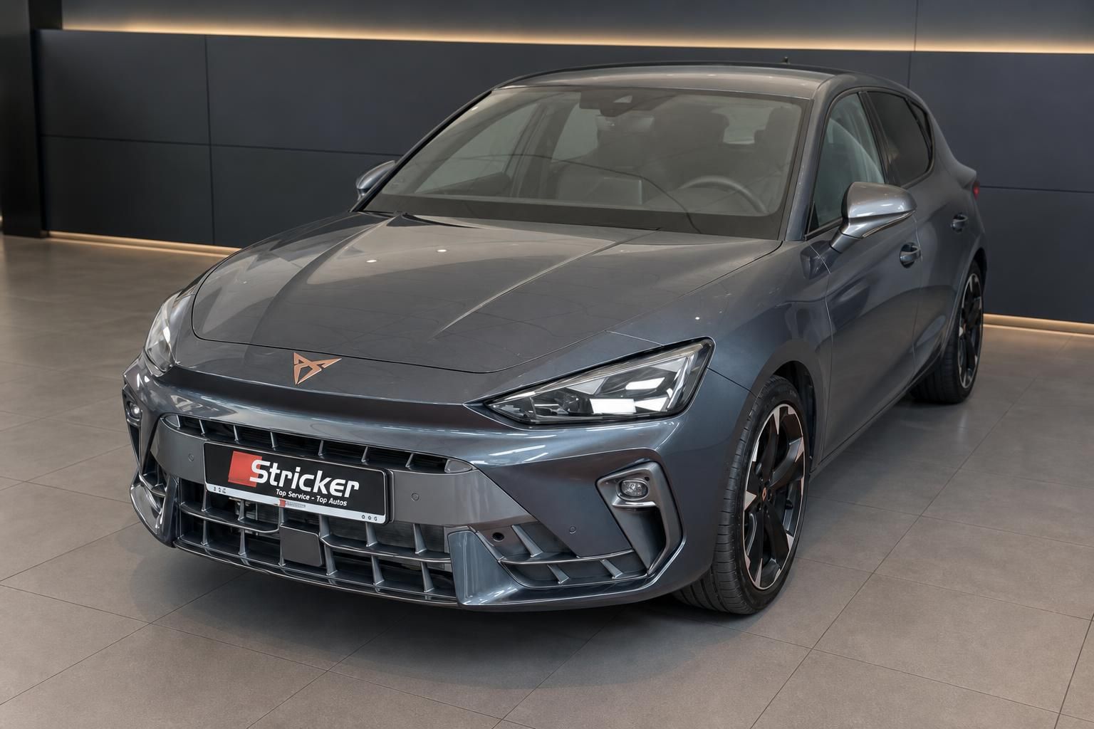 Cupra Leon Frontansicht in Grau metallic – Kompakt-Sportwagen mit markanter Frontschürze im Showroom