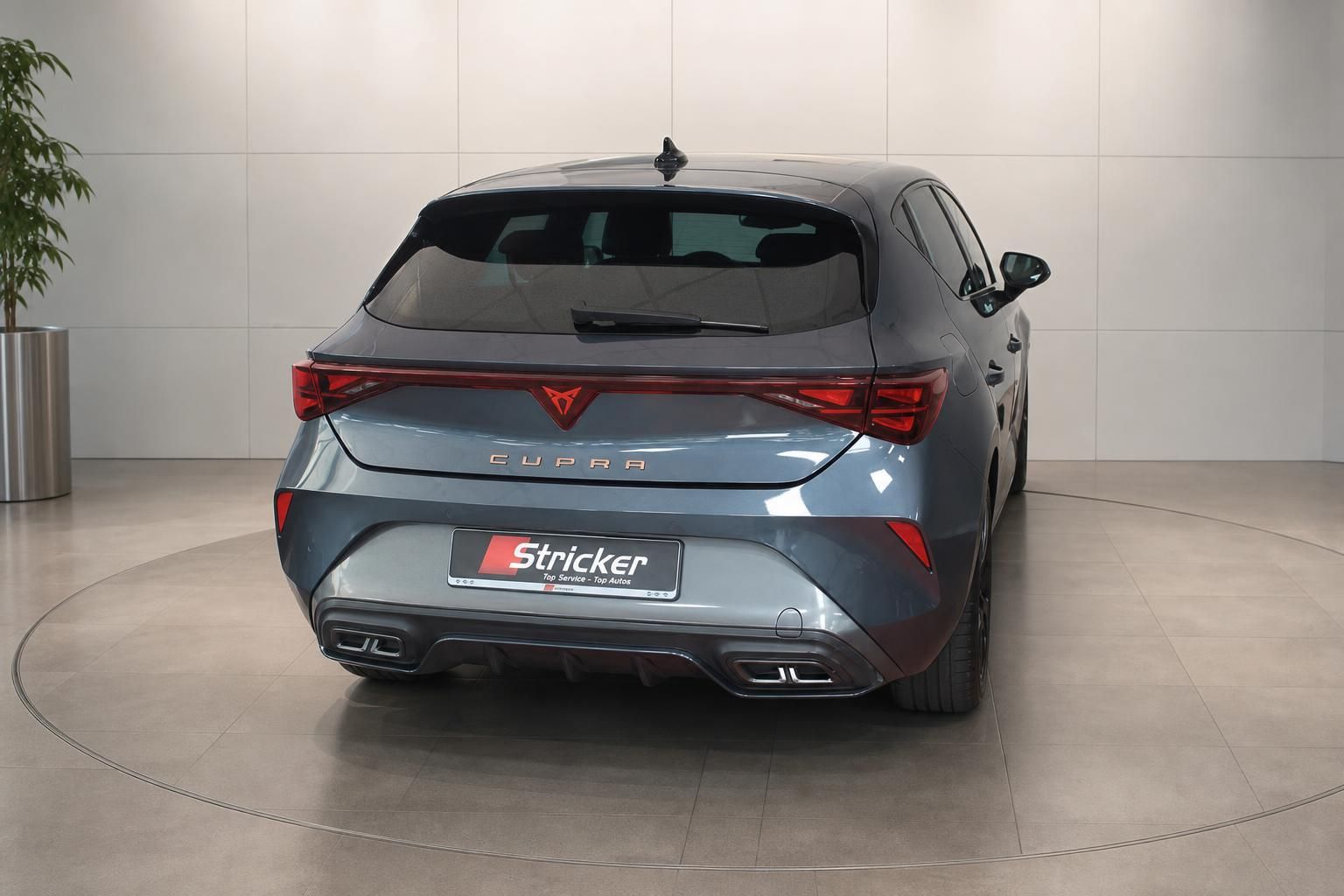 Cupra Leon Heckansicht in Grau-Blau metallic im Autohaus – sportlicher Kompaktwagen mit Quad-Auspuff