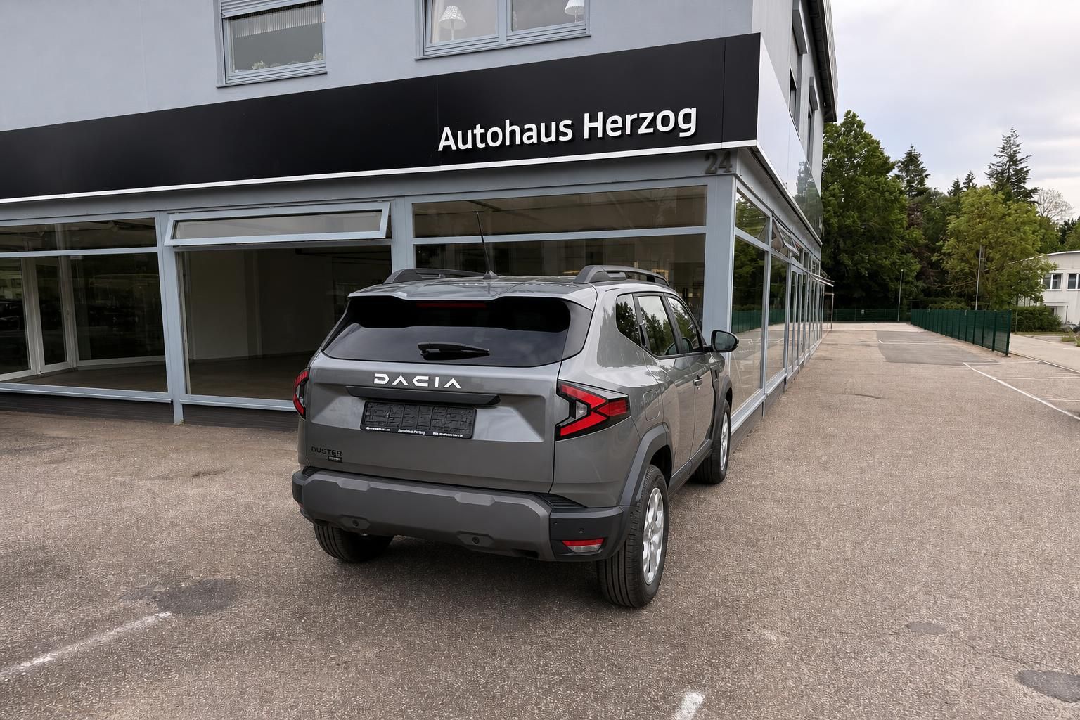 Dacia Duster SUV grau in Heckansicht vor Autohaus Herzog