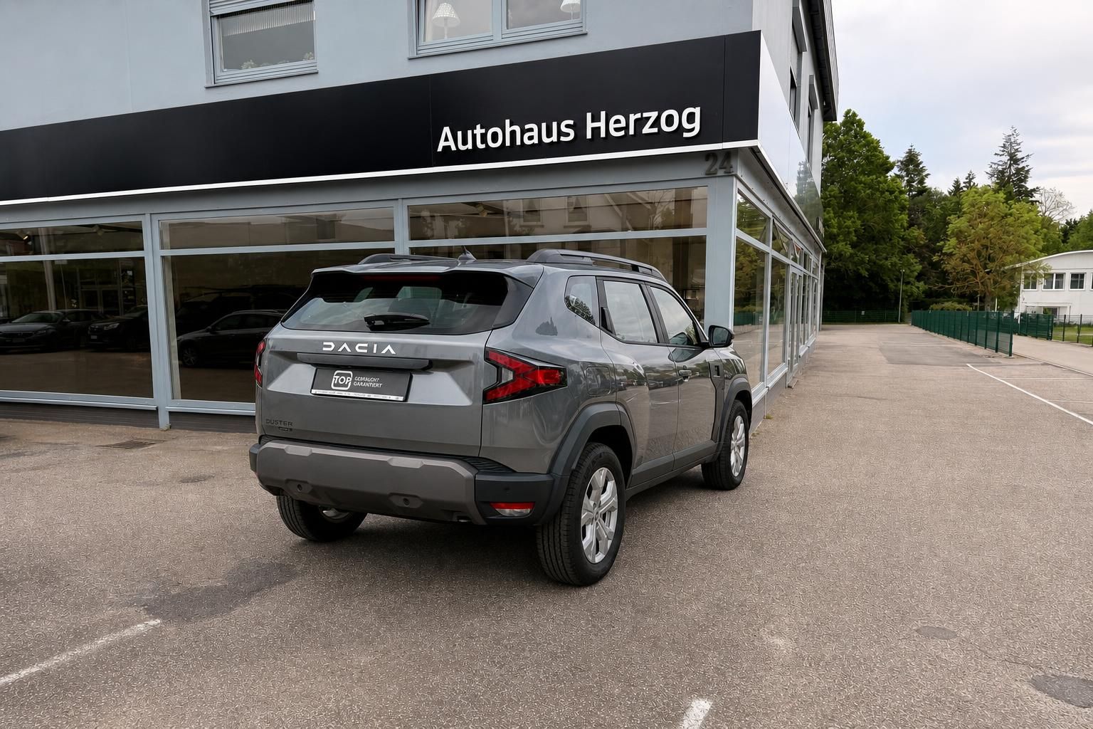Dacia Duster grau Heckansicht vor Autohaus Herzog Fassade