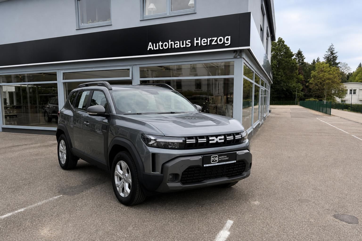 Dacia SUV grau in Frontansicht vor Autohaus Herzog