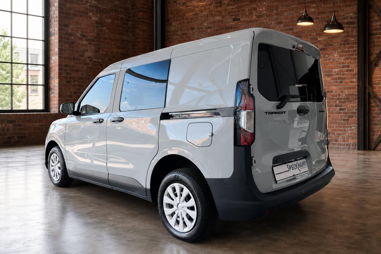 Ford Transit in Silber, Heckansicht schraeg im Industrie-Showroom