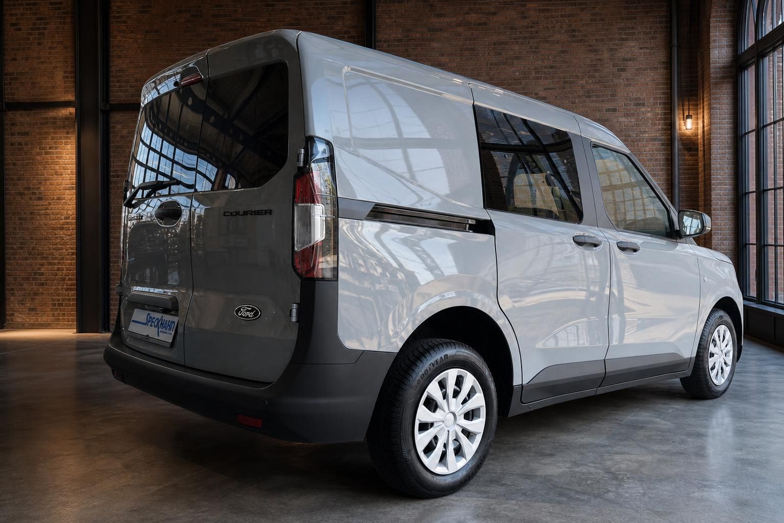 Ford Transit Courier in Silber, Heckansicht schraeg im Showroom