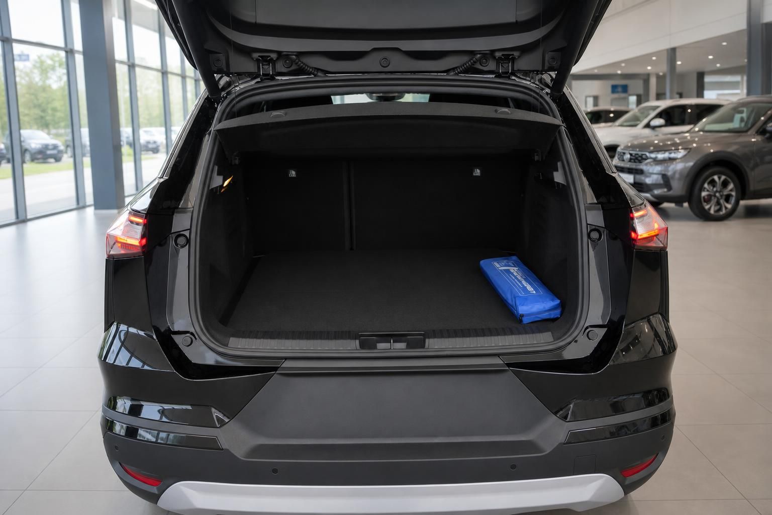 Geöffneter Kofferraum eines schwarzen SUV mit blauem Zubehör im Autohaus-Showroom