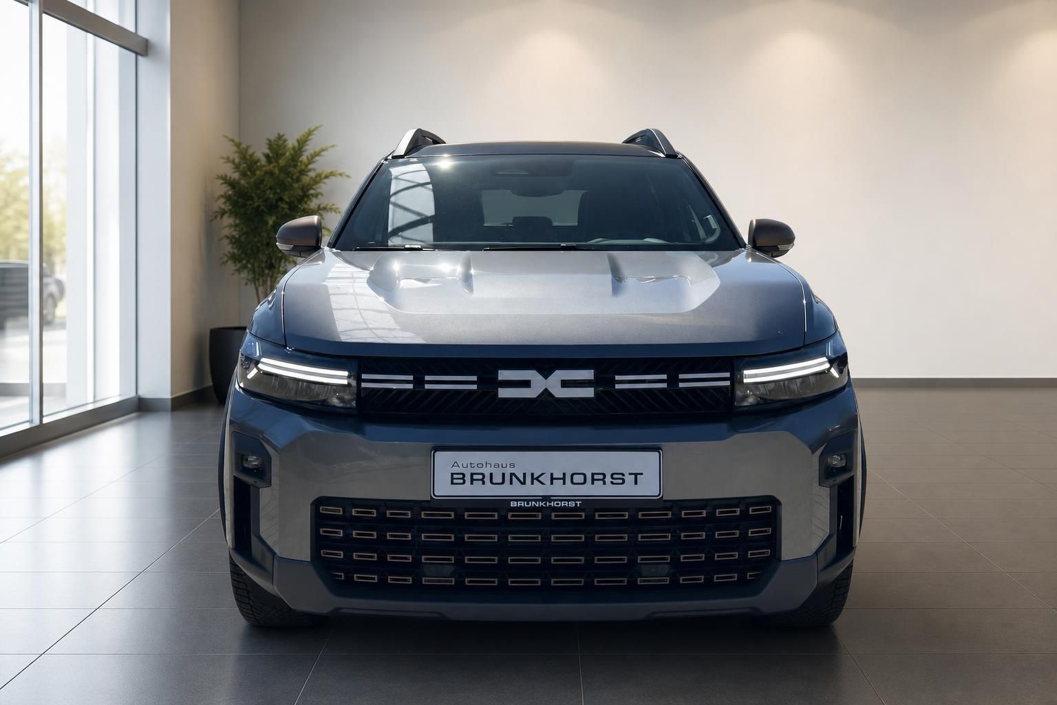 Dacia Bigster Frontansicht grau im Showroom - Markanter Kühlergrill und LED-Tagfahrlicht