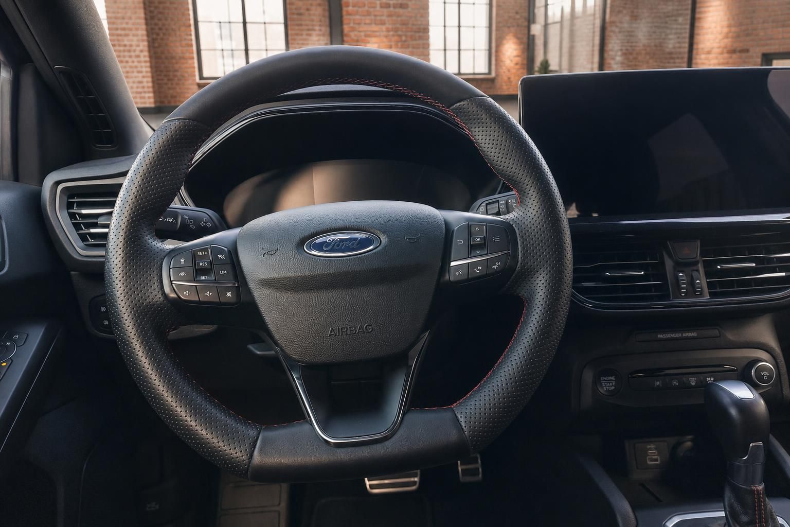Ford Focus Lenkrad Nahaufnahme mit Ford-Logo, Multifunktionstasten, Airbag-Beschriftung und Touchscreen im Hintergrund