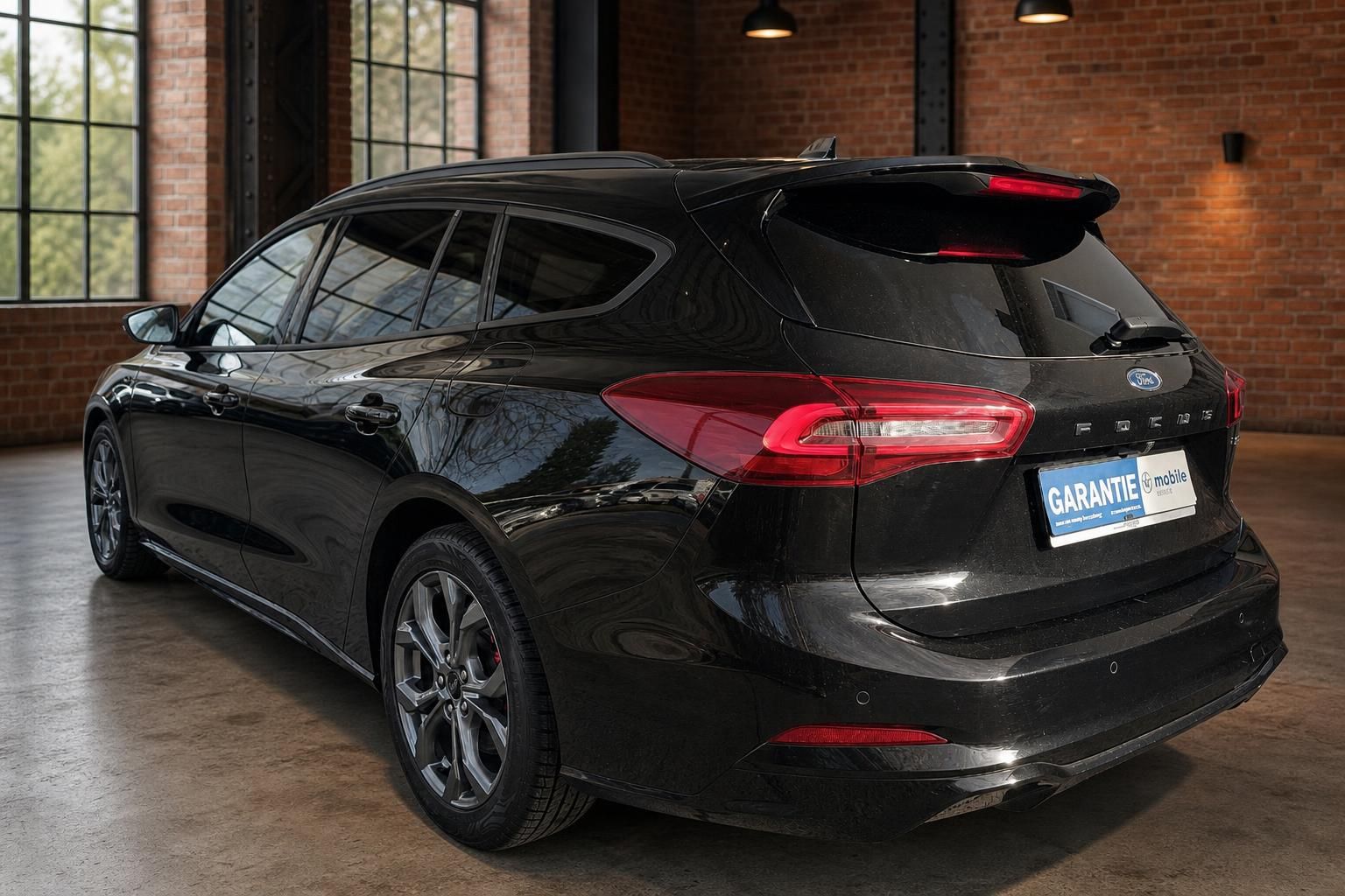 Ford Focus Turnier schwarz Heckansicht schräg links – Kombi in Industriehalle
