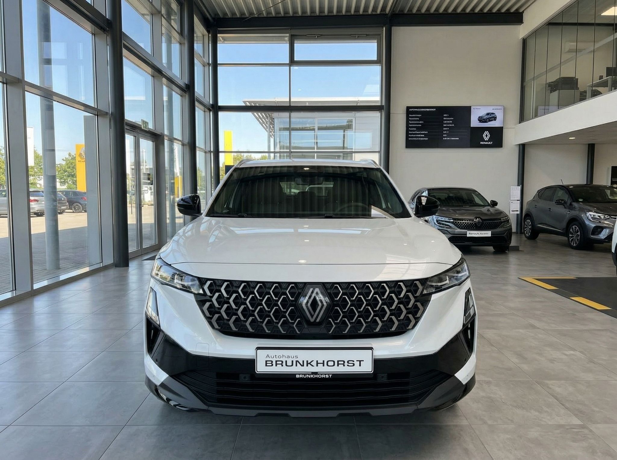 Weißer Renault Frontansicht im hellen Autohaus mit Glasfront und anderen Fahrzeugen