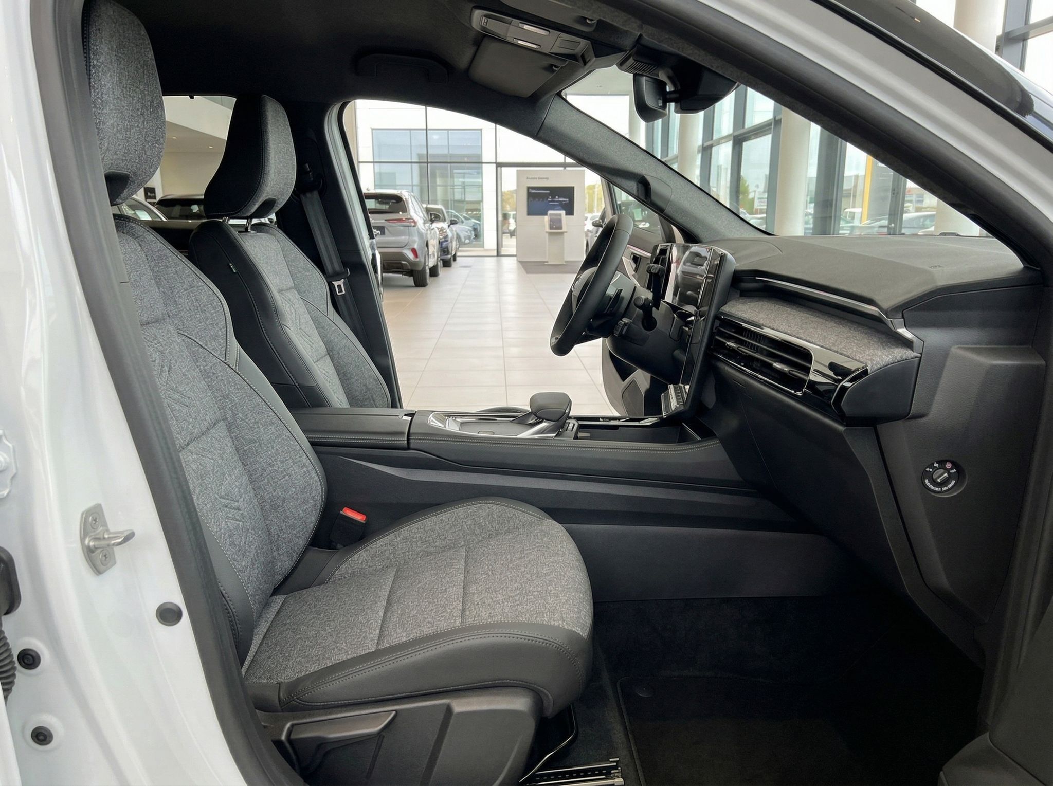 Fahrzeuginnenraum mit grauen Sitzen und Blick auf Armaturenbrett im Autohaus