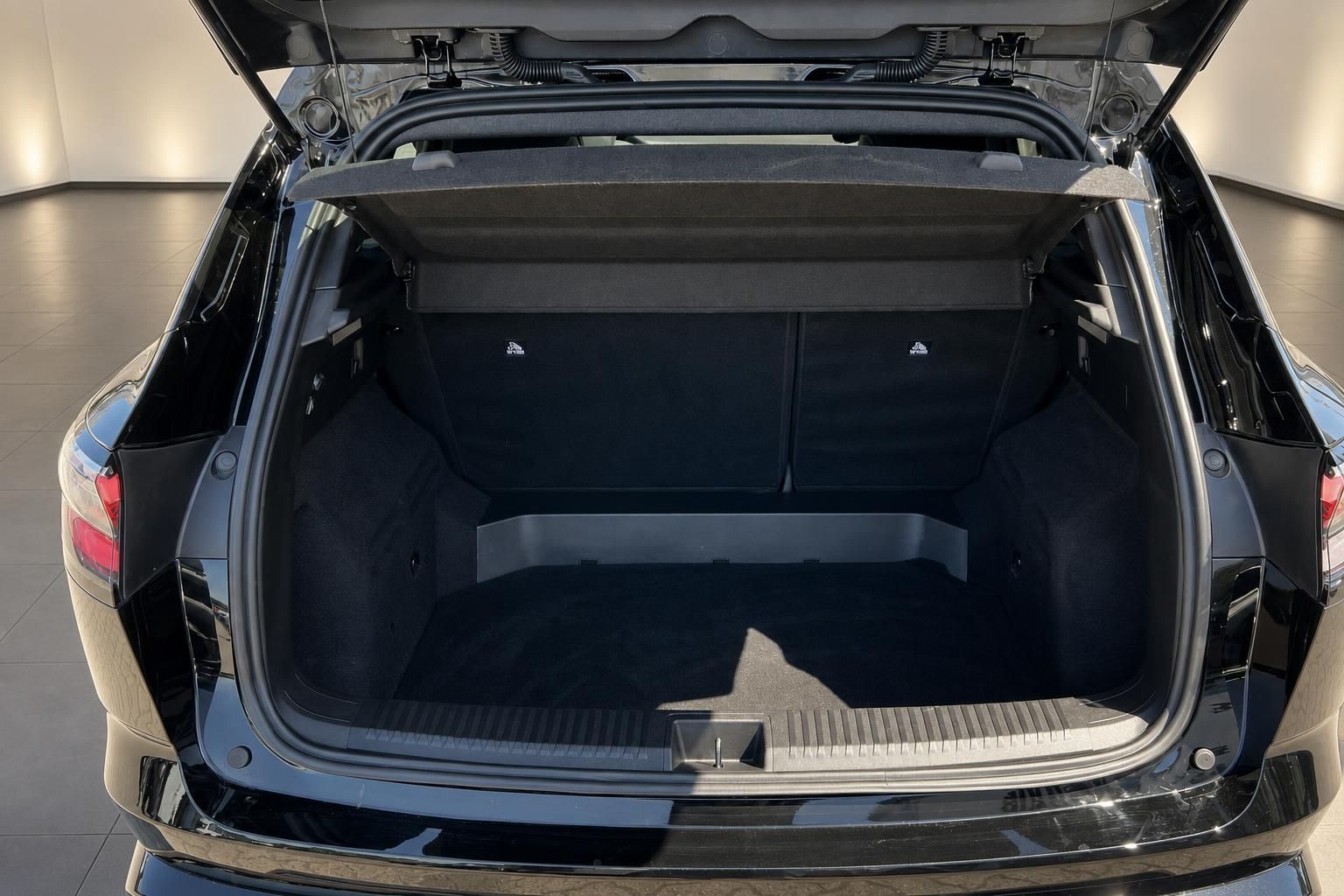 Kofferraum eines schwarzen SUV mit geoeffneter Heckklappe und Laderaumabdeckung