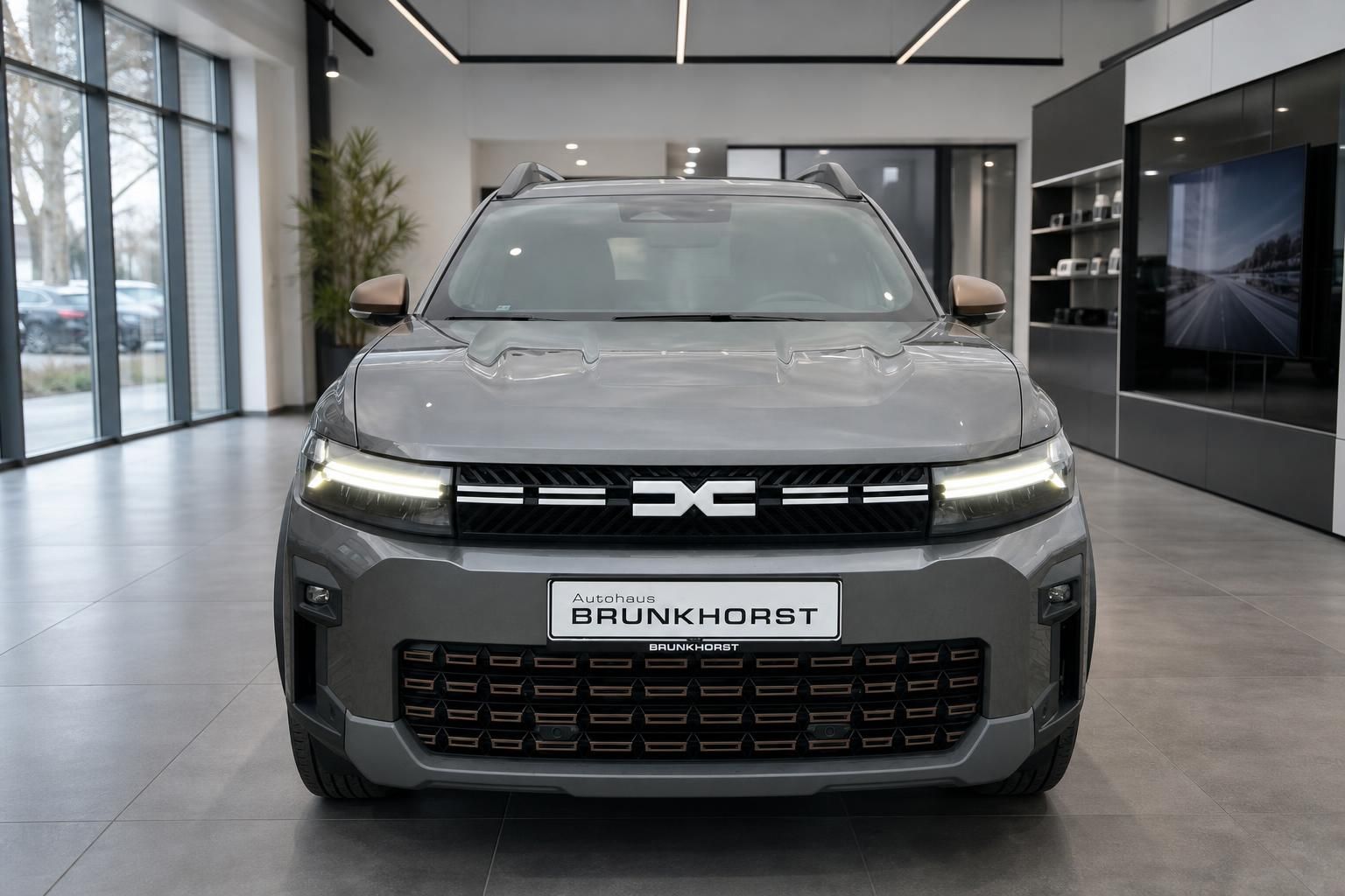 Dacia Bigster SUV grau - Frontansicht mit beleuchteten Scheinwerfern im Autohaus Brunkhorst