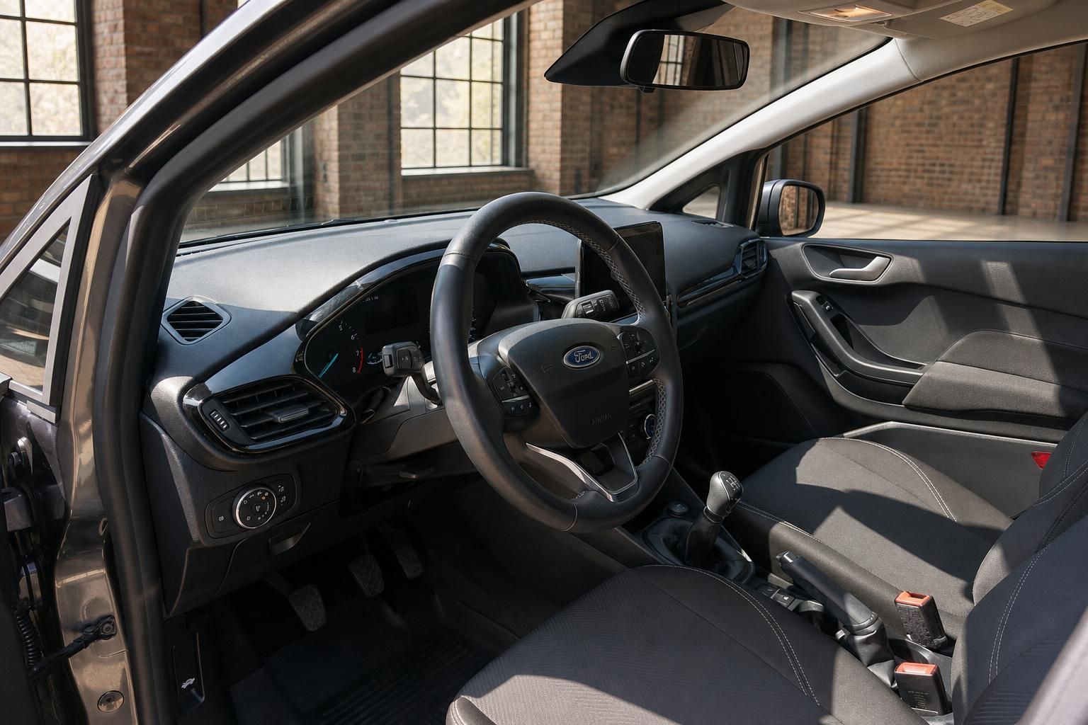 Ford Fiesta Innenraum – Lenkrad mit Ford-Logo, Schalthebel, Fahrersitz und Armaturenbrett in Schwarz