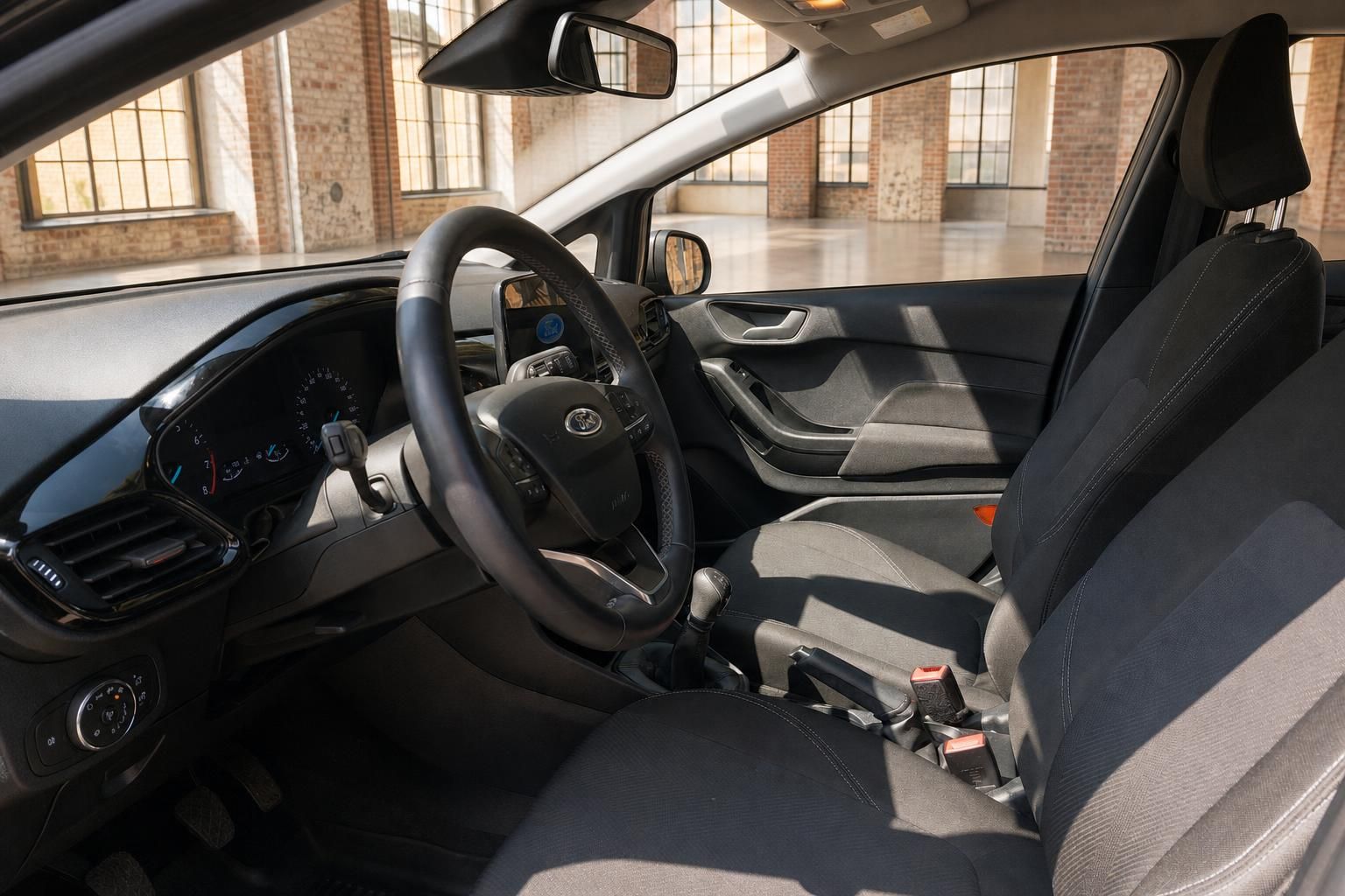 Ford Fiesta Innenraum – Fahrerseite mit Lenkrad, Schaltgetriebe und schwarzen Stoffsitzen