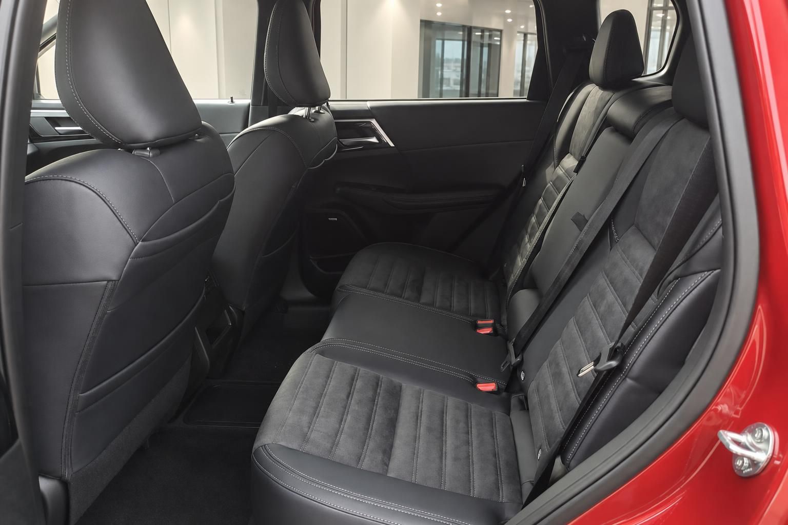 Rücksitzbank mit schwarzem Leder-Alcantara-Bezug und roten Sicherheitsgurten im SUV
