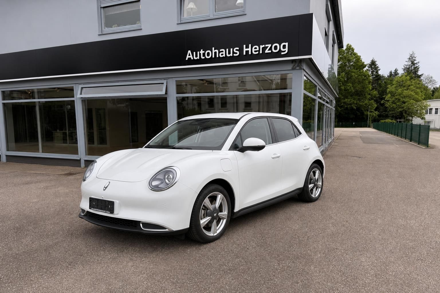 Weisses Elektrofahrzeug in Frontansicht vor Autohaus Herzog geparkt
