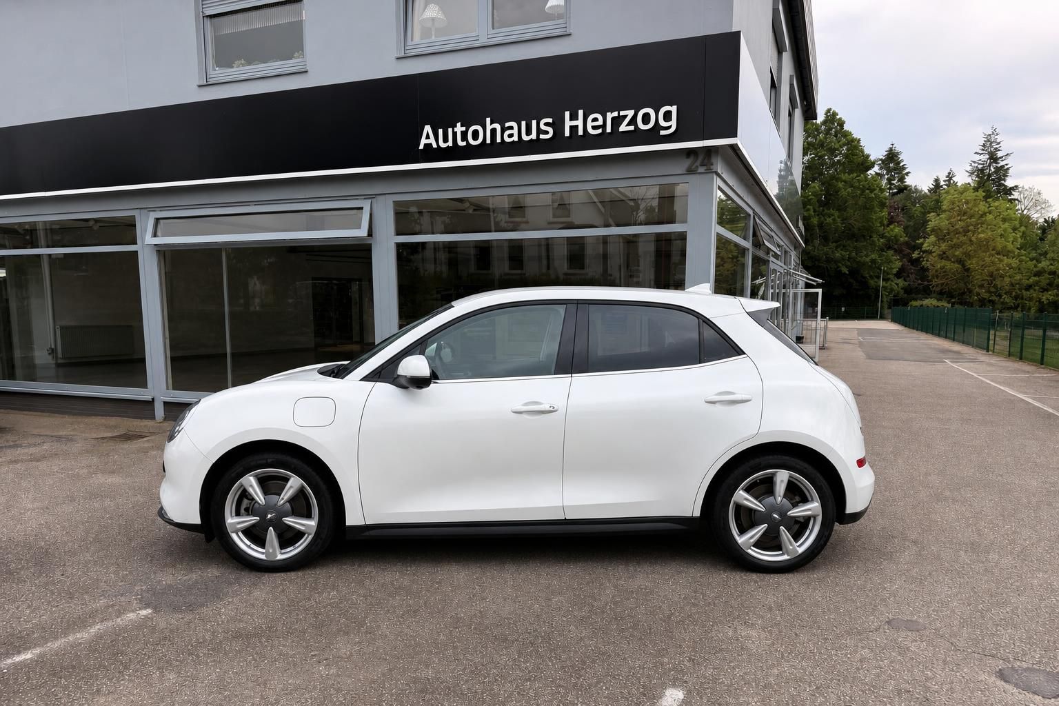 Weißer ORA Elektroauto Seitenansicht vor Autohaus Herzog