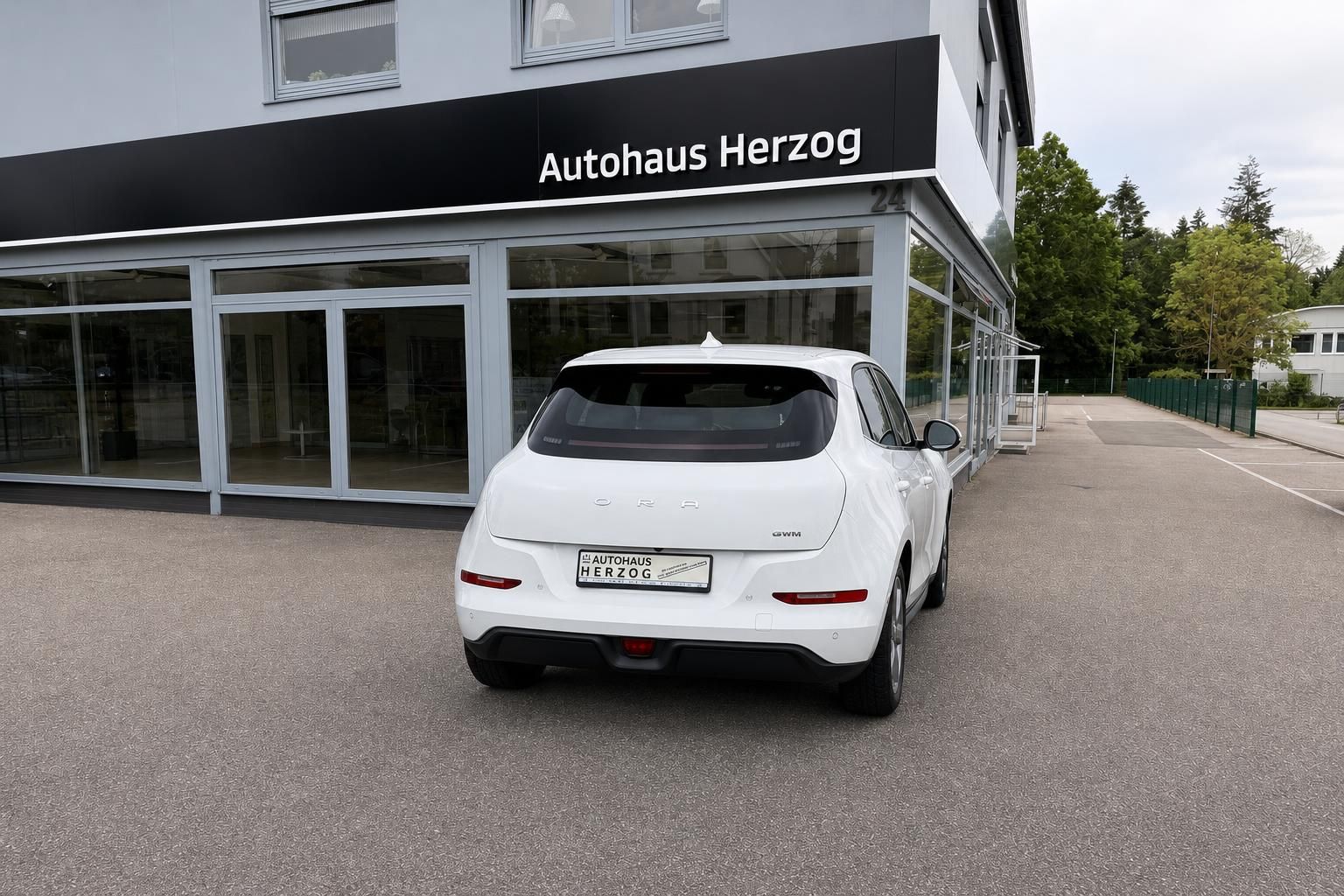 Weißer ORA Elektro-SUV Heckansicht vor Autohaus Herzog