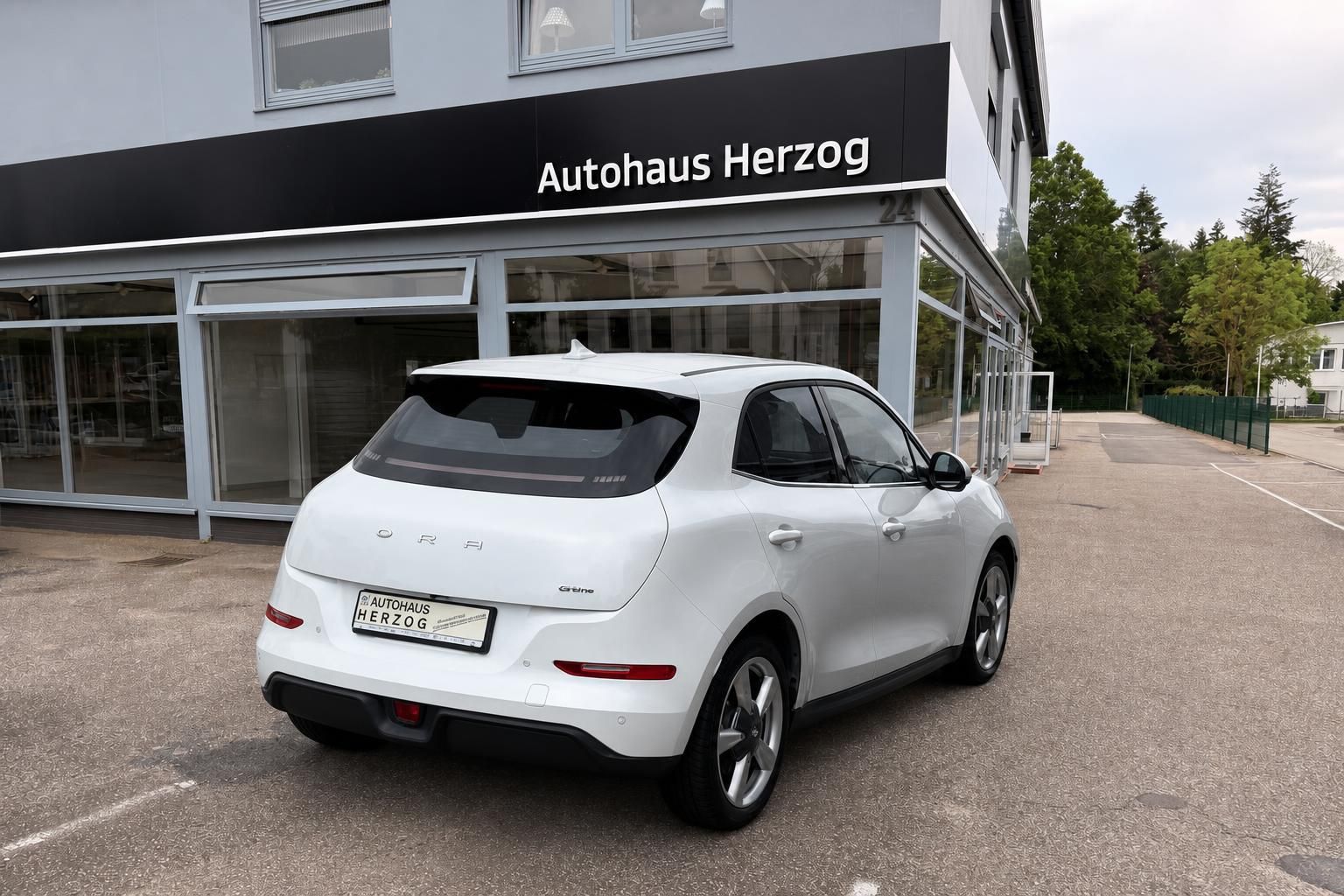 Weißer ORA Kompakt-SUV Heck seitlich vor Autohaus Herzog