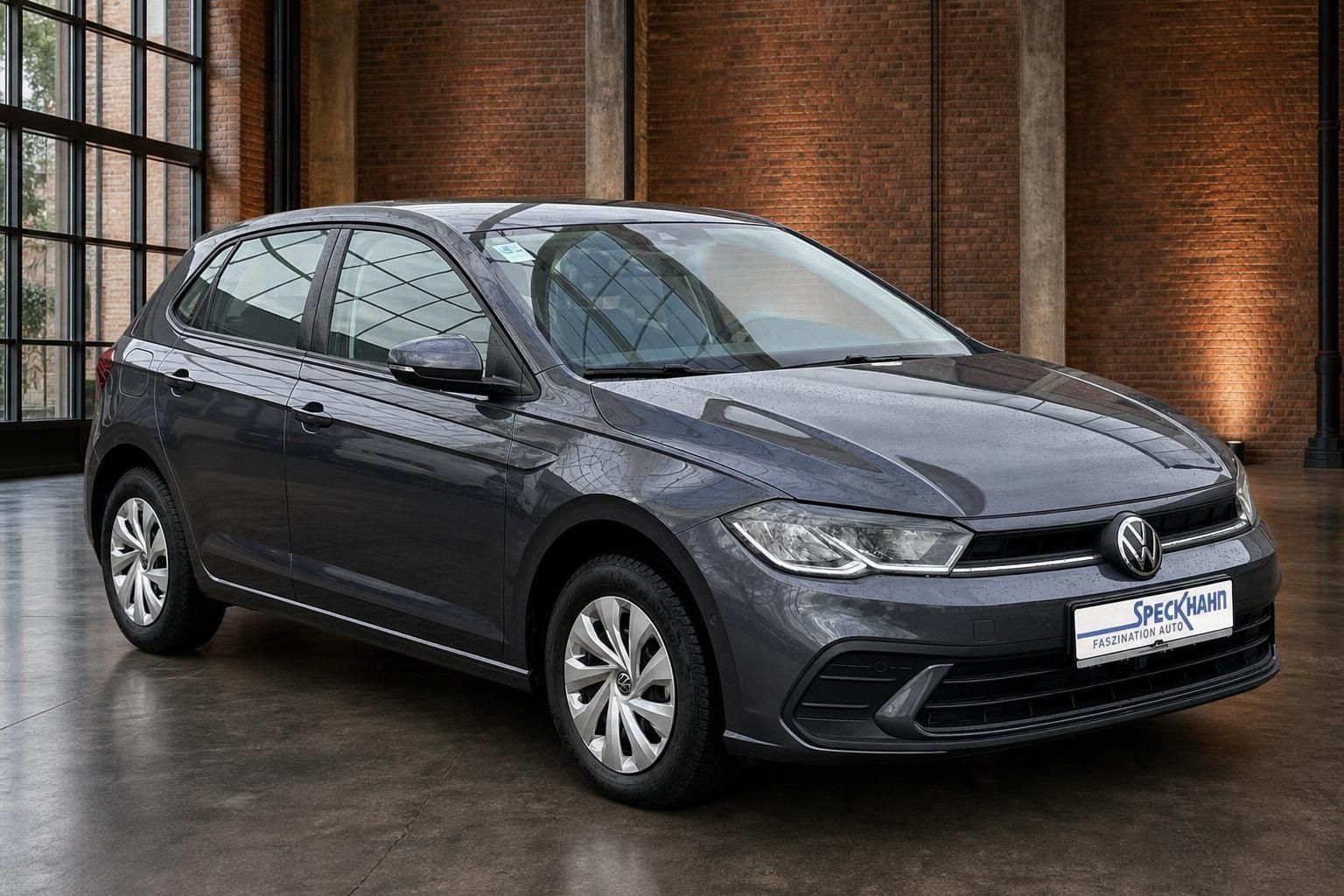 VW Polo grau Frontansicht seitlich vor Backsteinwand mit Saeulen