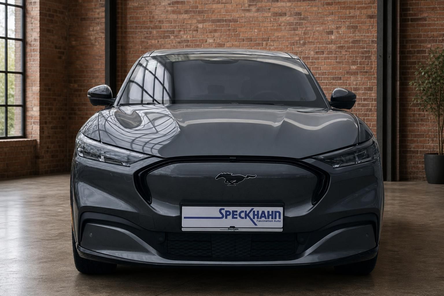 Ford Mustang Mach-E grau Frontansicht mit Speckhahn Kennzeichenhalter in Industriehalle