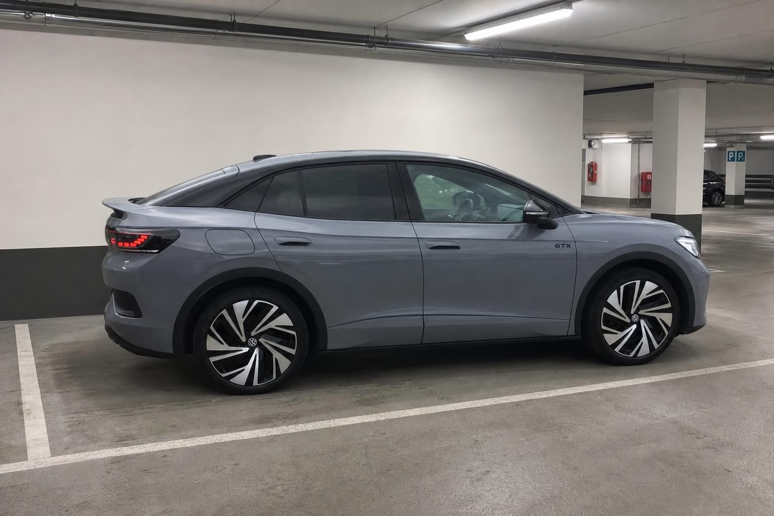 VW ID.4 GTX grau, Seitenansicht von hinten im Parkhaus