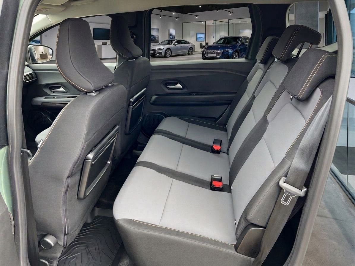 Dacia Rücksitzbank mit grau-weißer Polsterung und Blick auf Autohaus Showroom