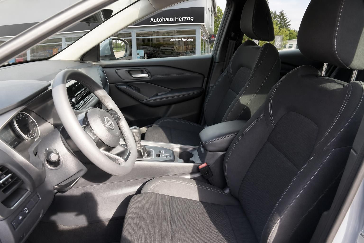 Nissan Innenraum mit schwarzer Ausstattung, Fahrer- und Beifahrersitz, Lenkrad und Cockpit-Ansicht