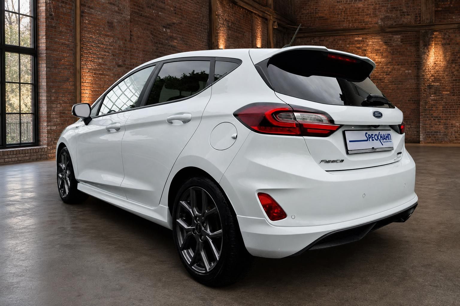 Ford Fiesta weiß Heckansicht schräg mit Spoiler vor Backsteinwand