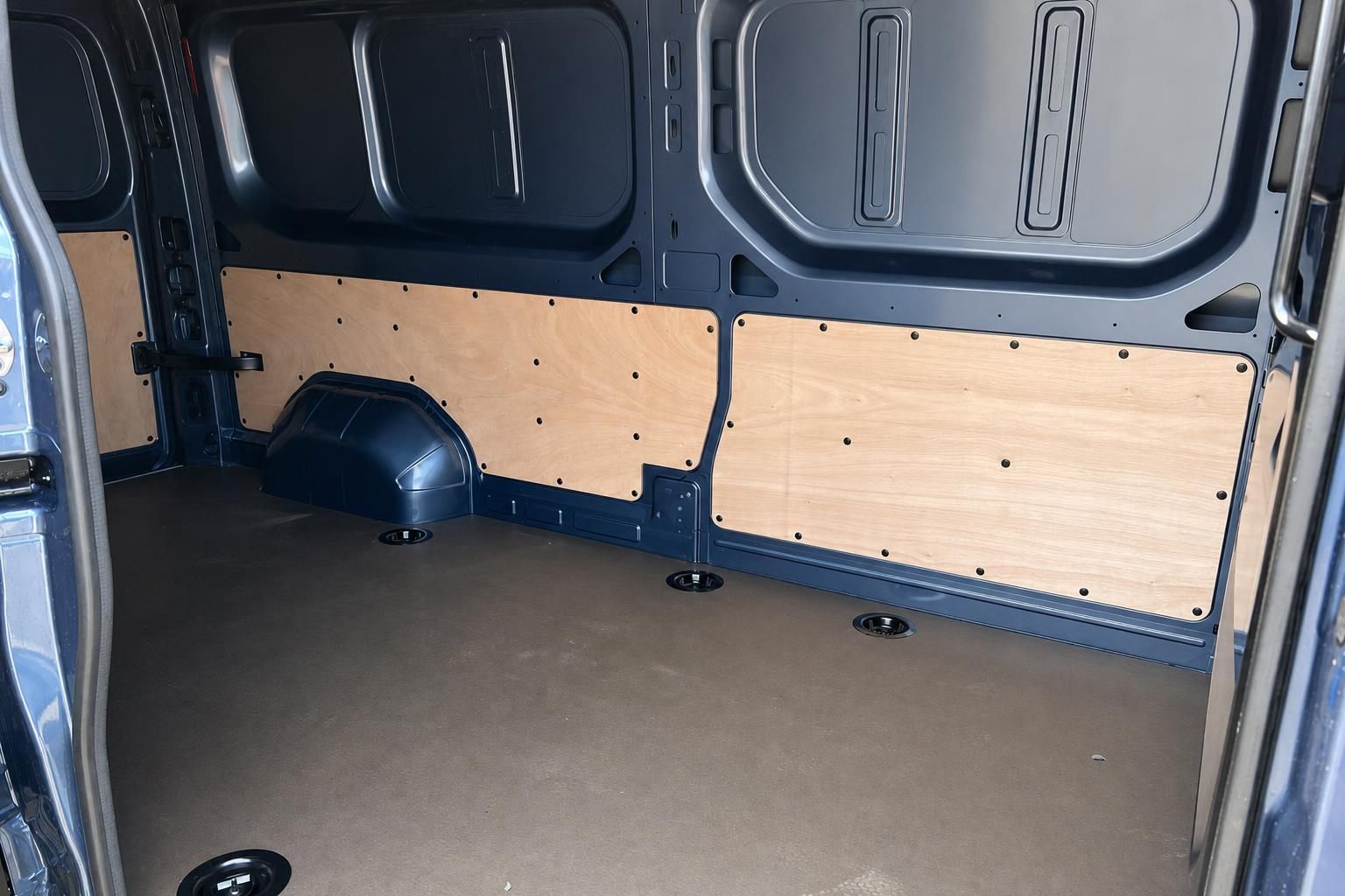 Geräumiger Laderaum eines Transporters mit Holzverkleidung und praktischen Befestigungspunkten