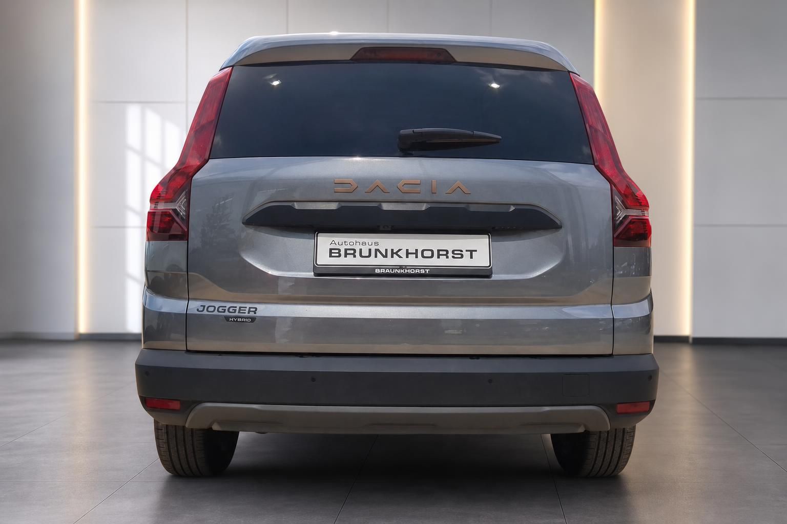 Dacia Jogger Hybrid Heckansicht in Grau mit roten Rücklichtern und Modellschriftzug