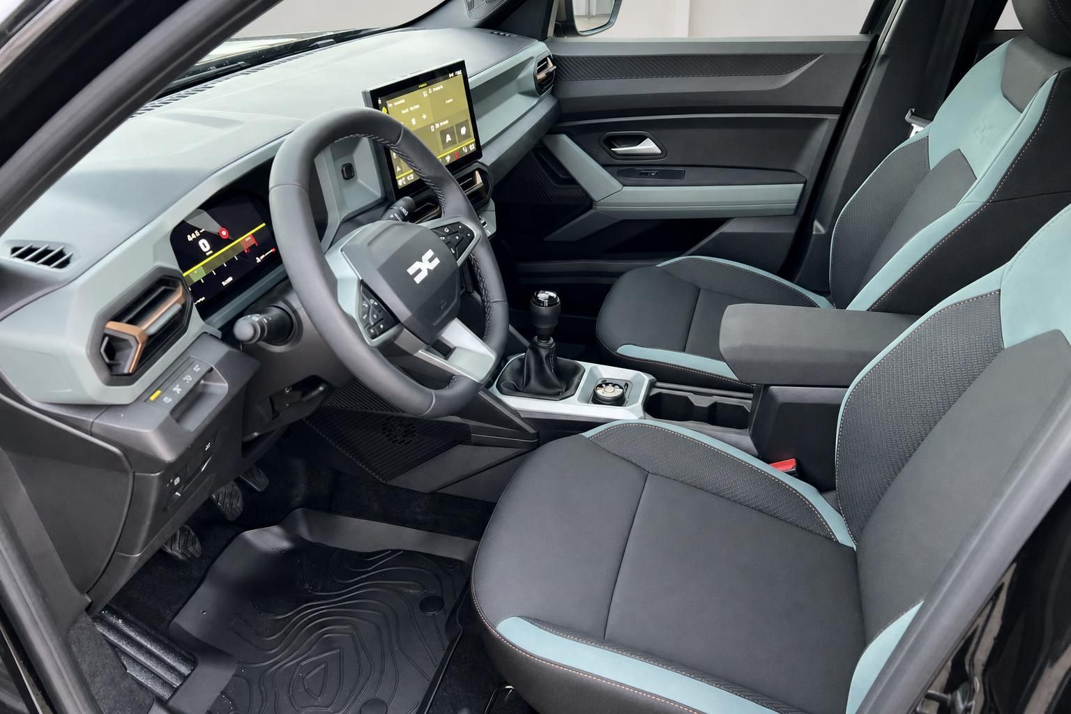 Dacia Bigster Fahrerplatz mit digitalem Cockpit, Lenkrad und türkisfarbenen Sitzdetails