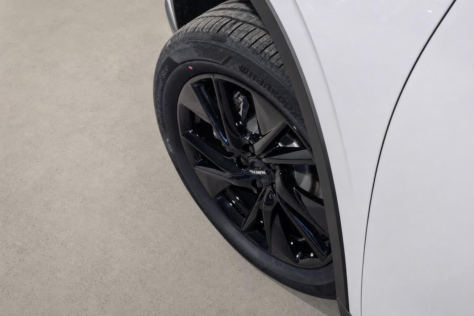 Detailansicht schwarzes Alufelge mit Hankook Reifen am weißen Fahrzeug