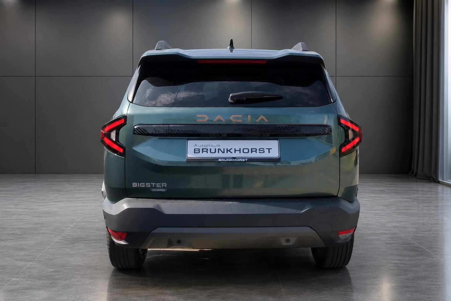 Dacia Bigster Hybrid in Gruen, Heckansicht im Showroom