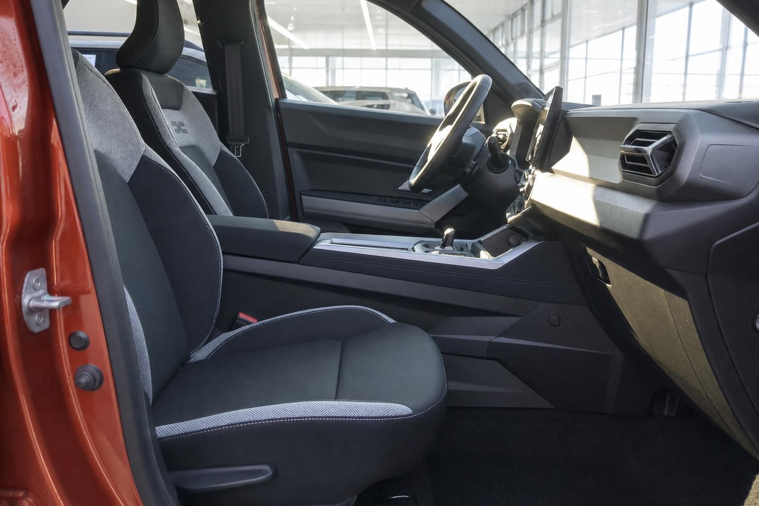 Innenraum eines modernen Fahrzeugs mit schwarzen Sportsitzen und orangener Karosserie im Autohaus
