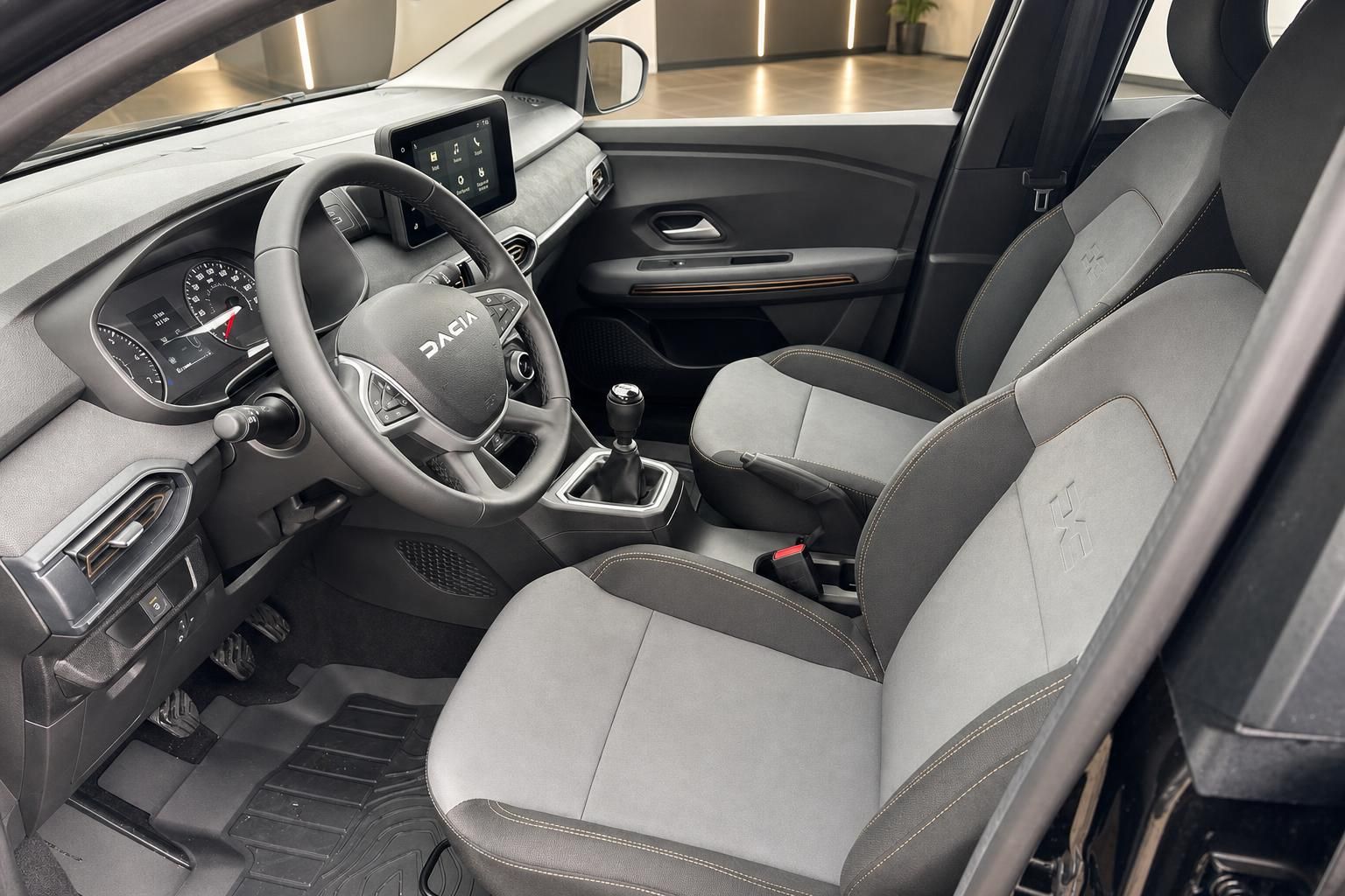 Dacia Fahrzeug Innenraum mit grauem Lenkrad, Touchscreen und manueller Schaltung
