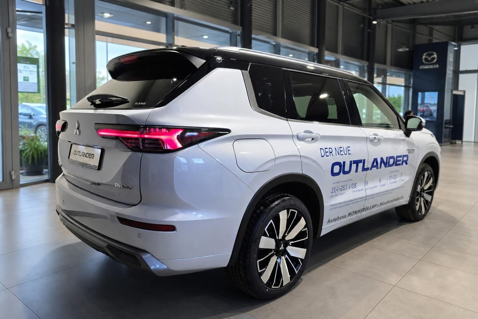 Mitsubishi Outlander PHEV in Weiss, Heckansicht mit Alufelgen im Showroom