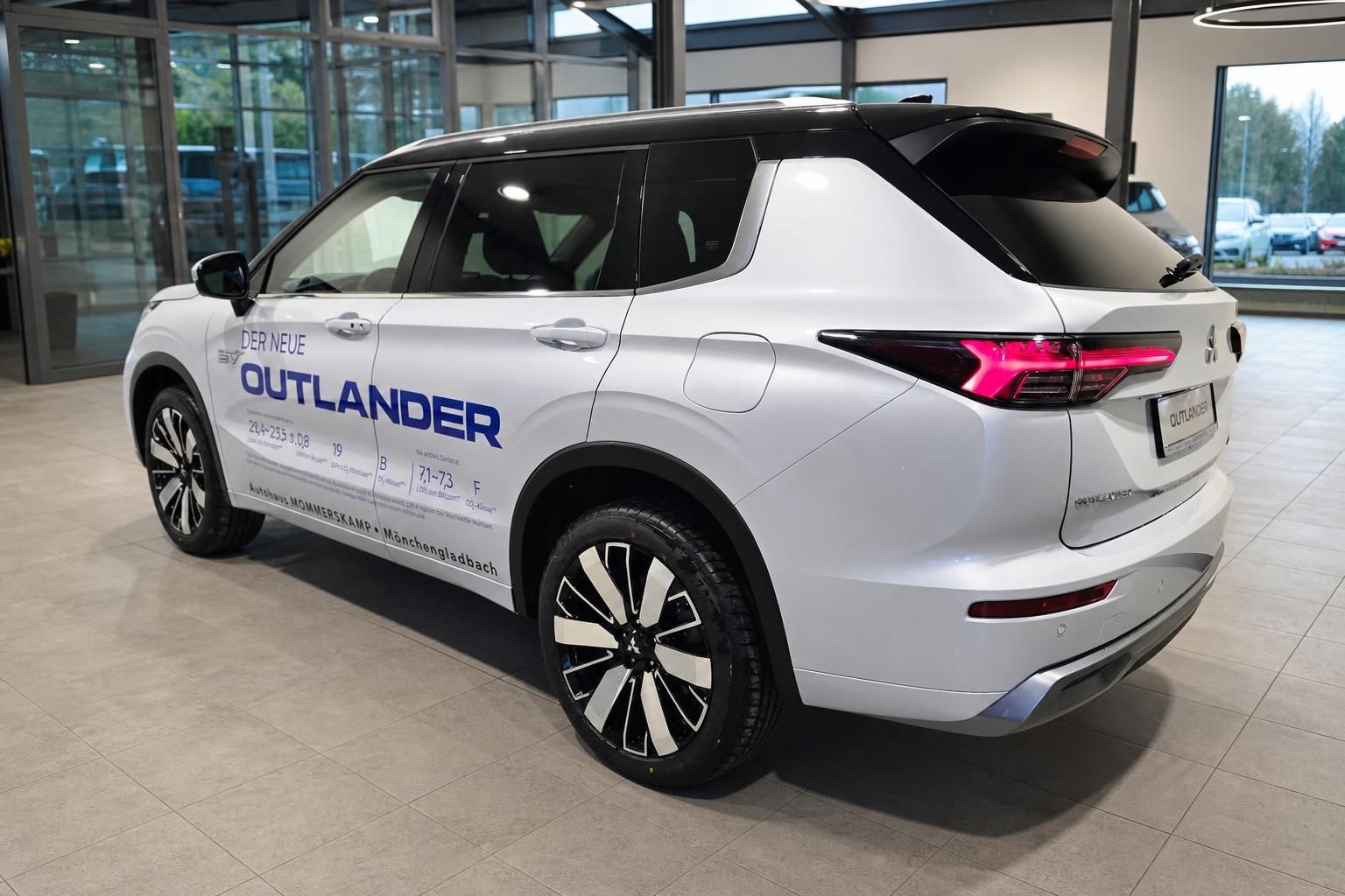 Mitsubishi Outlander PHEV in Weiss, Heck-Seitenansicht im Showroom