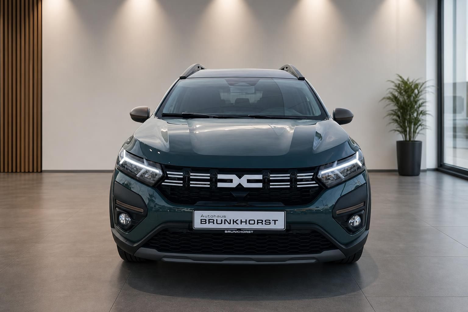 Dacia SUV grün metallic Frontansicht im Autohaus Showroom mit LED-Scheinwerfern