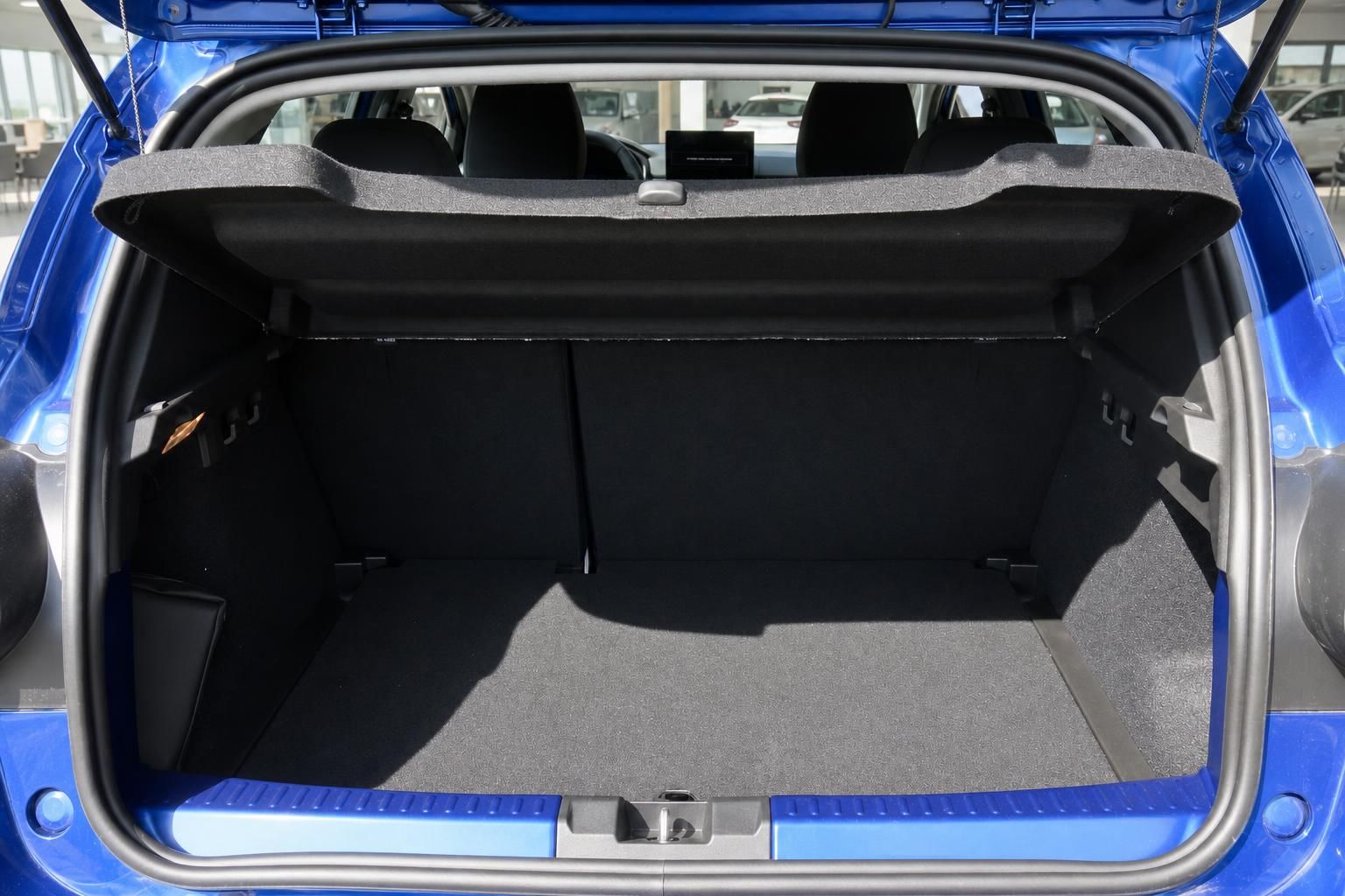 Kofferraum eines blauen Fahrzeugs mit schwarzer Innenausstattung und geöffneter Heckklappe
