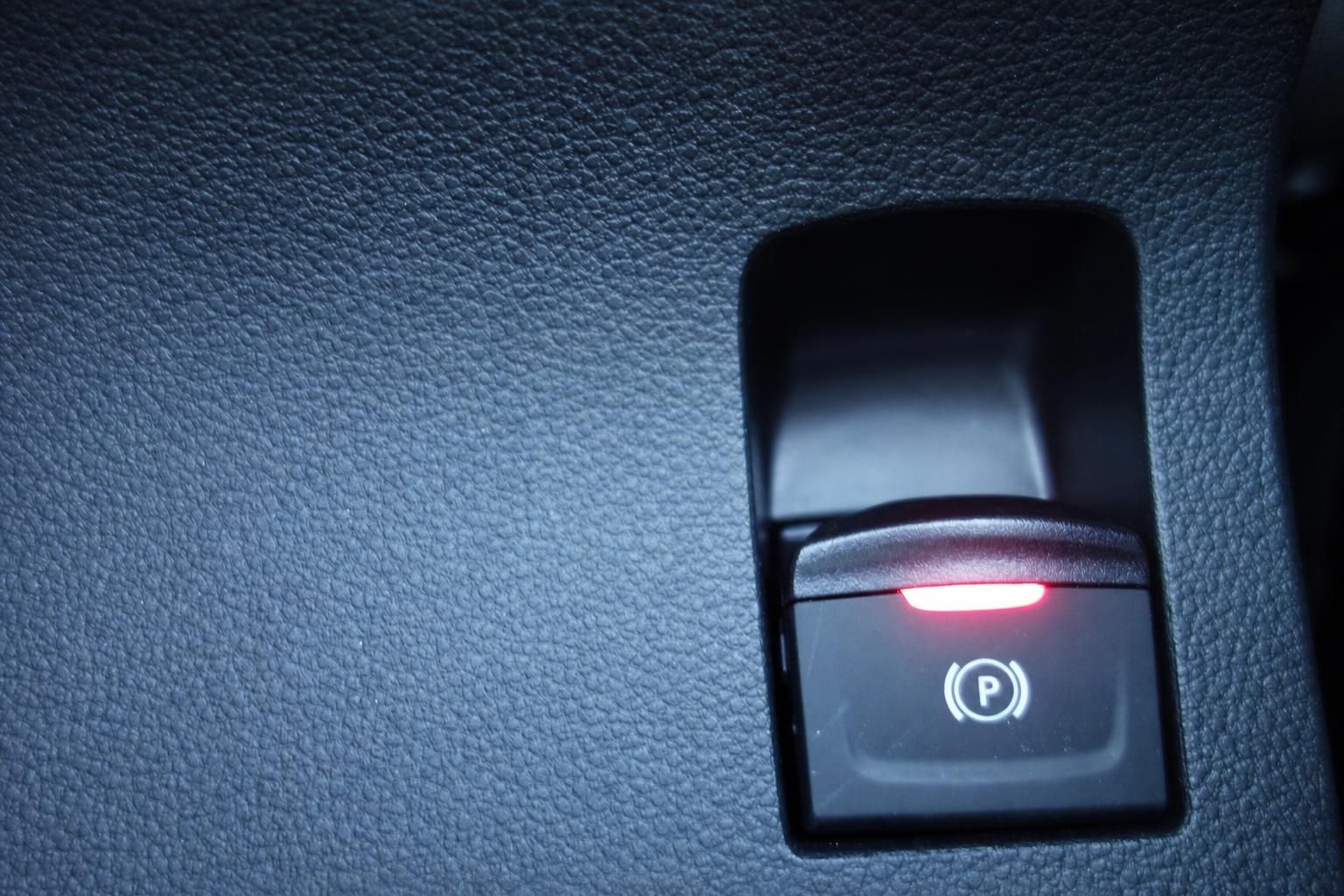 Beleuchteter Parkbremsen-Schalter mit roter LED-Anzeige im Fahrzeuginnenraum