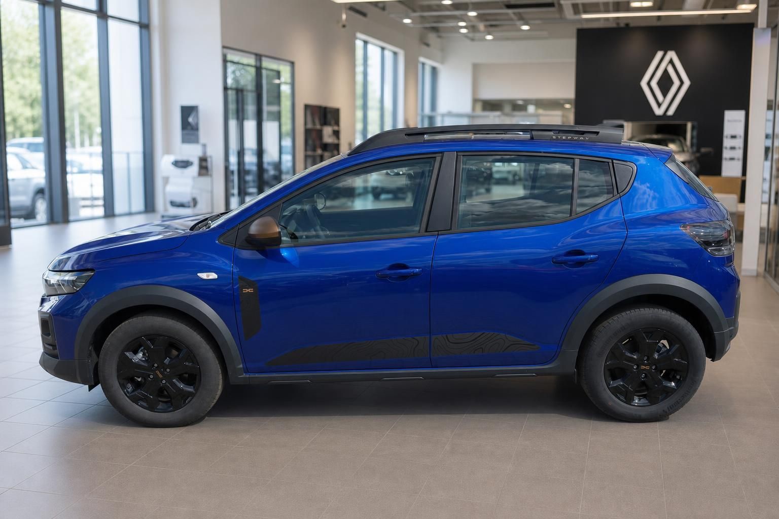 Blauer Dacia Sandero SUV Seitenansicht im Autohaus mit schwarzen Felgen und Renault Logo