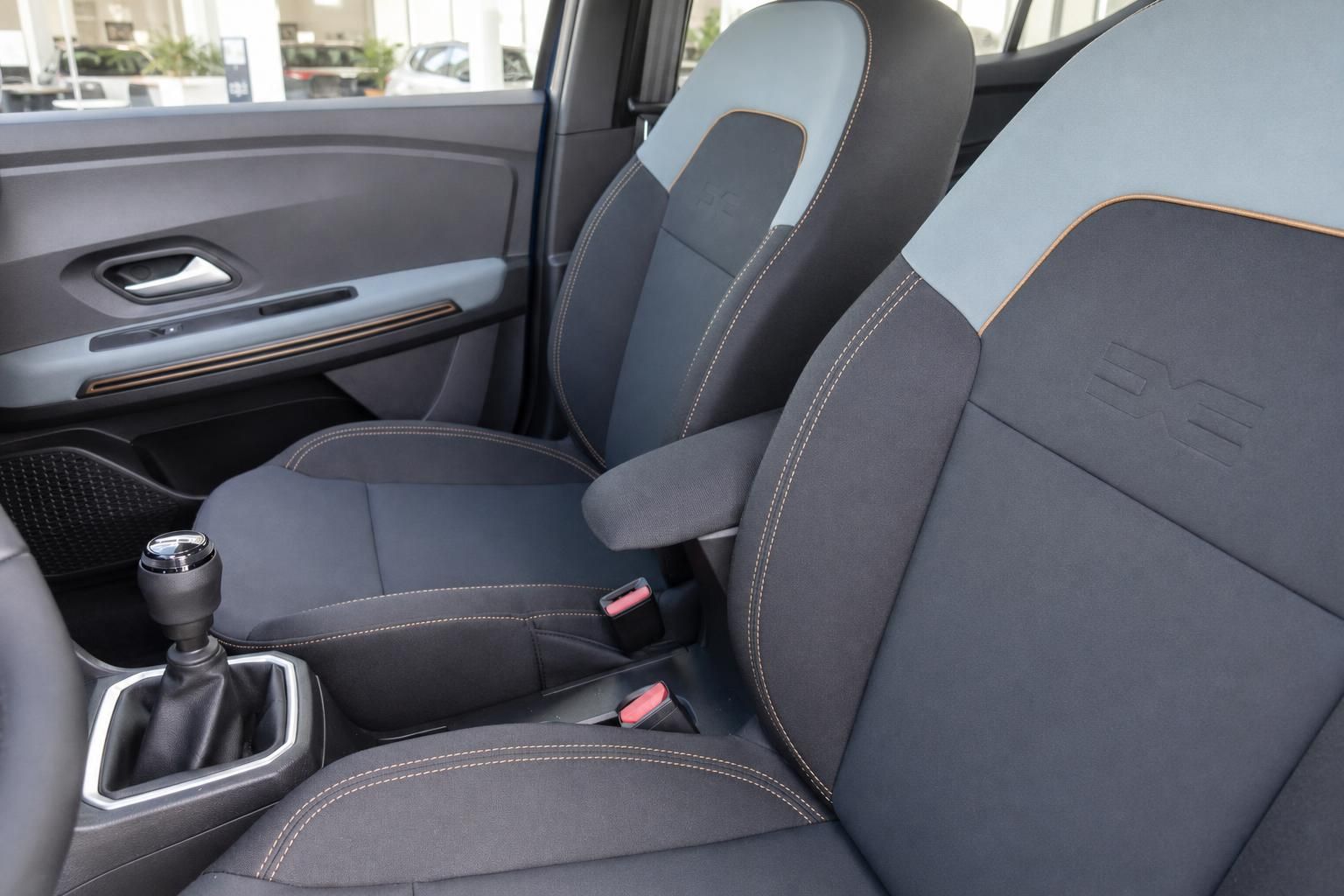 Innenraum Dacia Sandero mit grau-orangen Sitzen, Schaltknauf und Mittelkonsole Detail