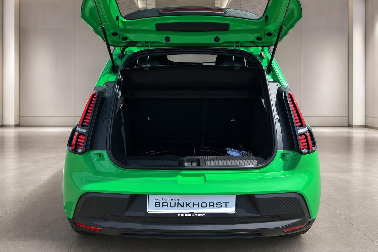 Grünes Elektroauto mit geöffneter Heckklappe und Kofferraum, Ansicht von hinten