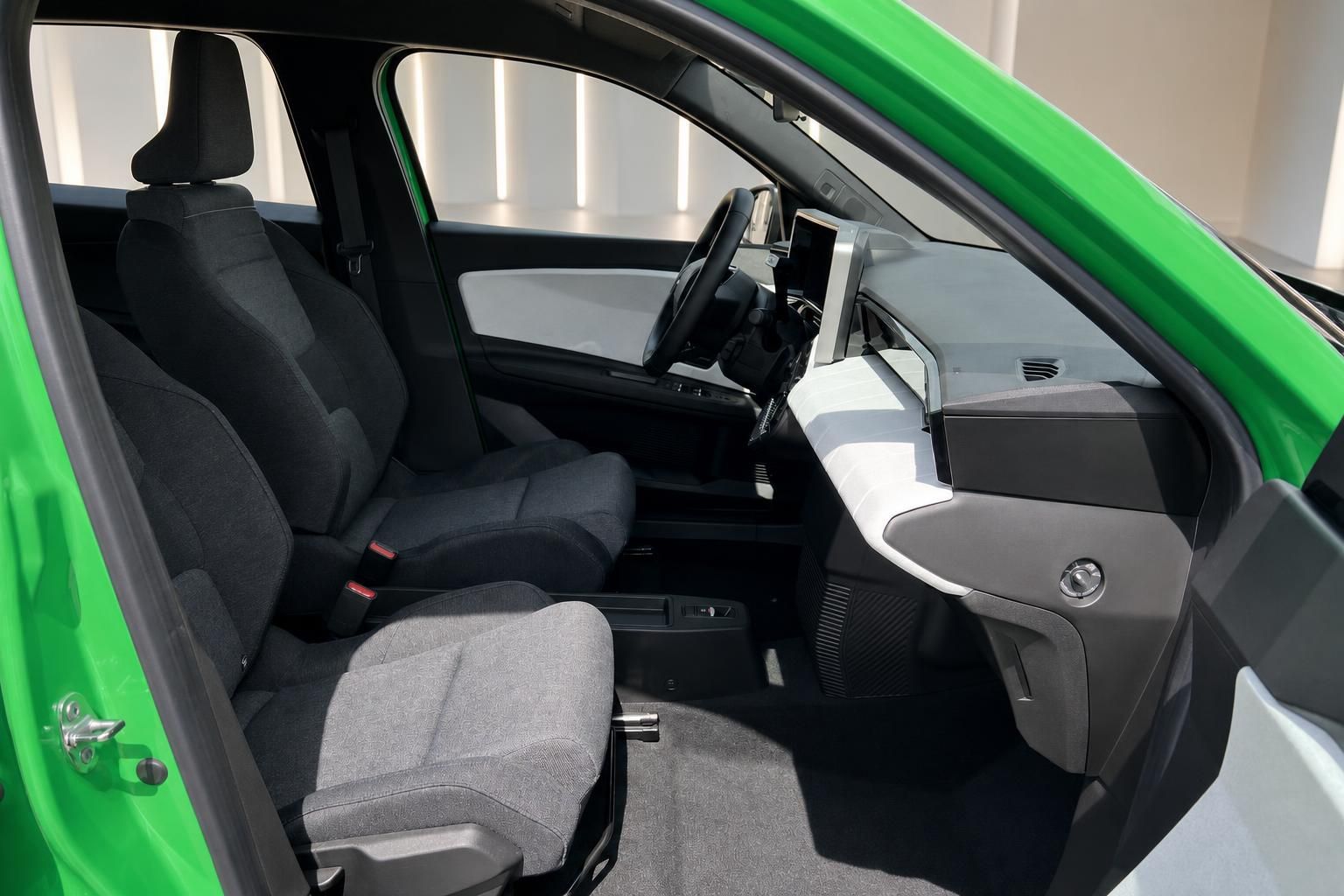 Innenraum eines gruenen Fahrzeugs mit schwarzen Sitzen und modernem Cockpit