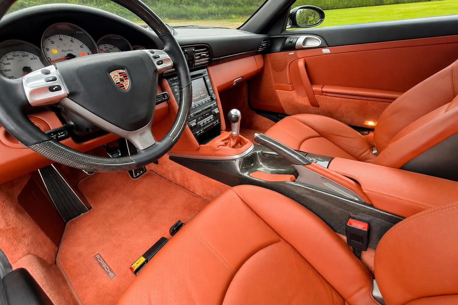 Porsche Fahrerinnenraum mit orangefarbener Lederausstattung und Carbon-Details