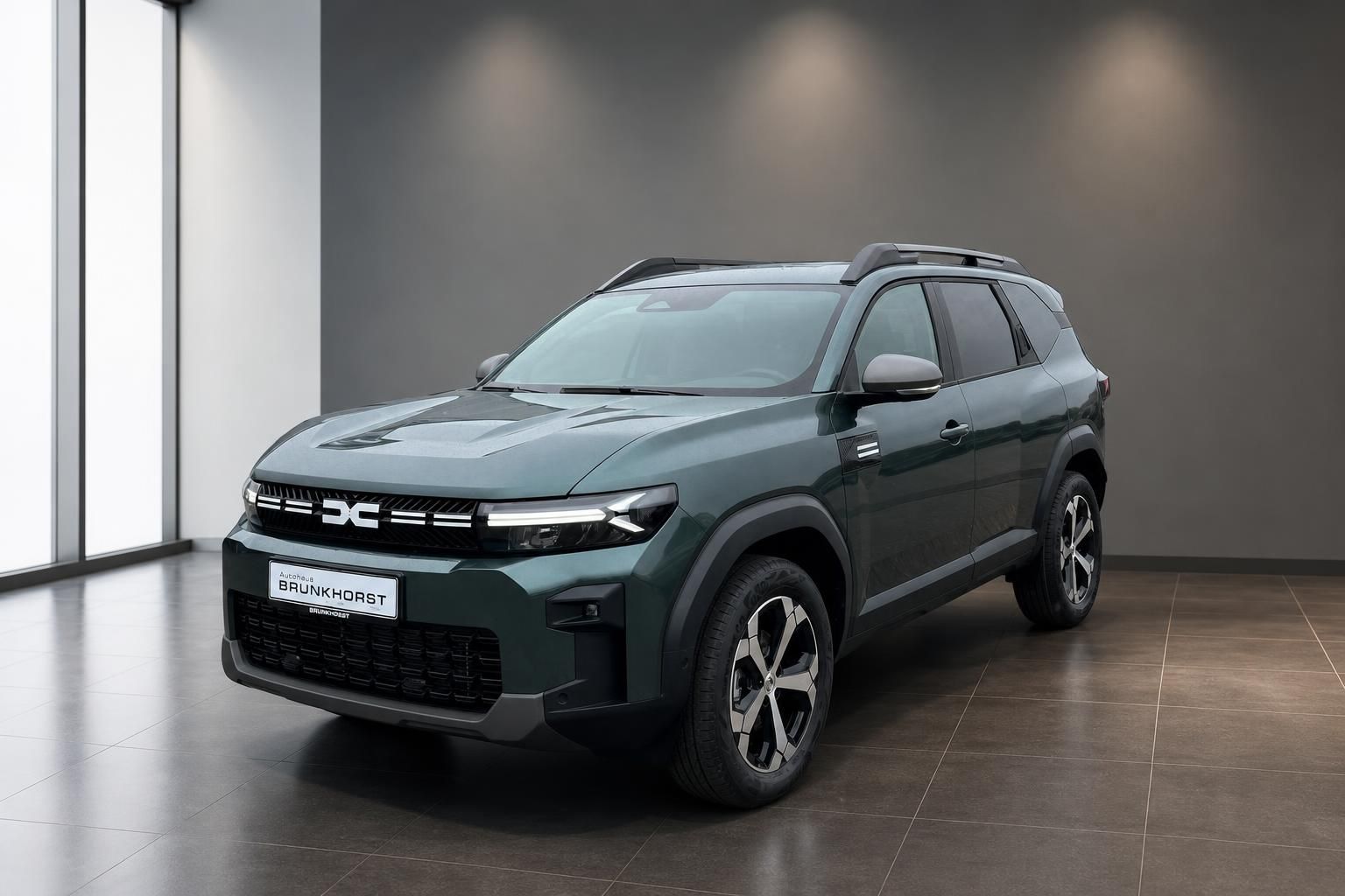 Dacia SUV Seitenansicht in grau-grün metallic mit LED-Scheinwerfern im Autohaus Showroom