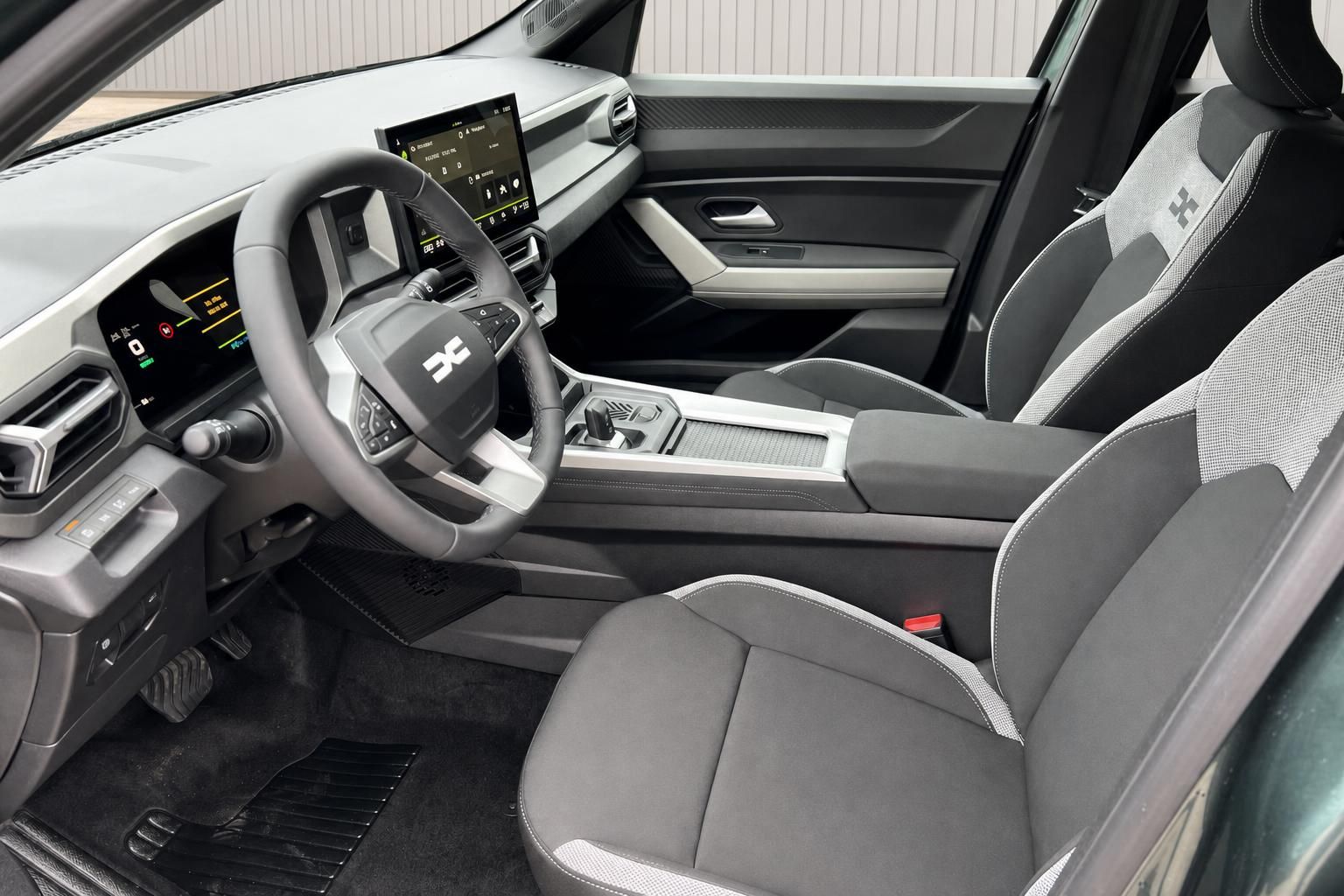 Dacia Fahrersitz und Cockpit-Detail mit Lenkrad, Digital-Display und Mittelkonsole in grau