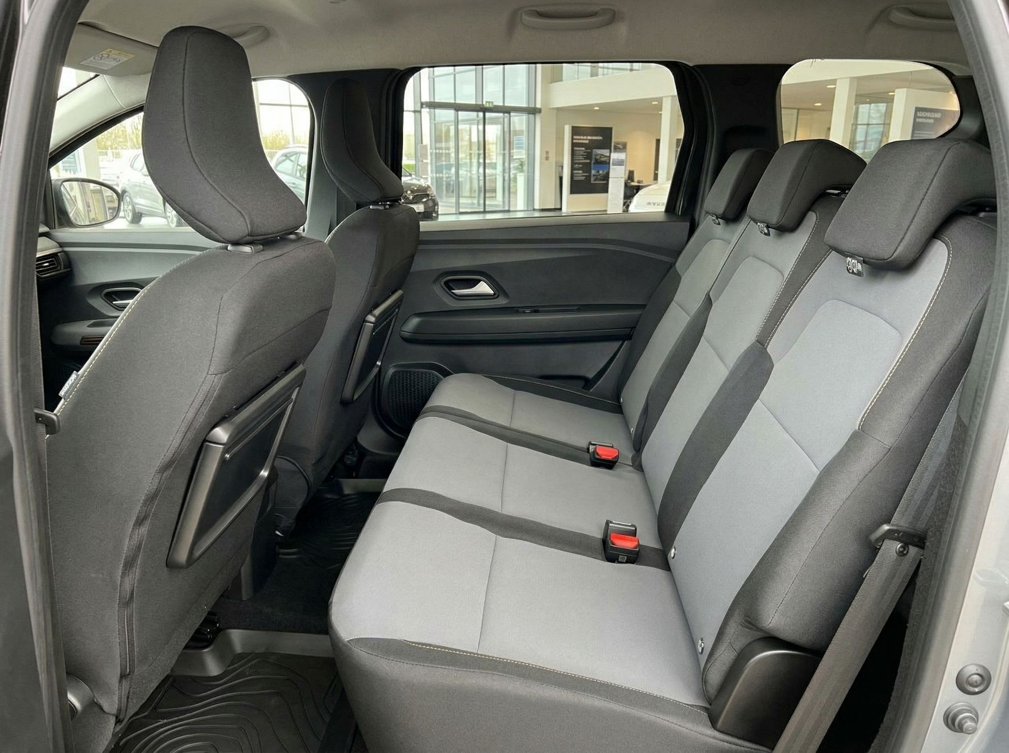 Dacia Rücksitzbank mit grauen Polstern und Sicherheitsgurten im Fahrzeuginnenraum