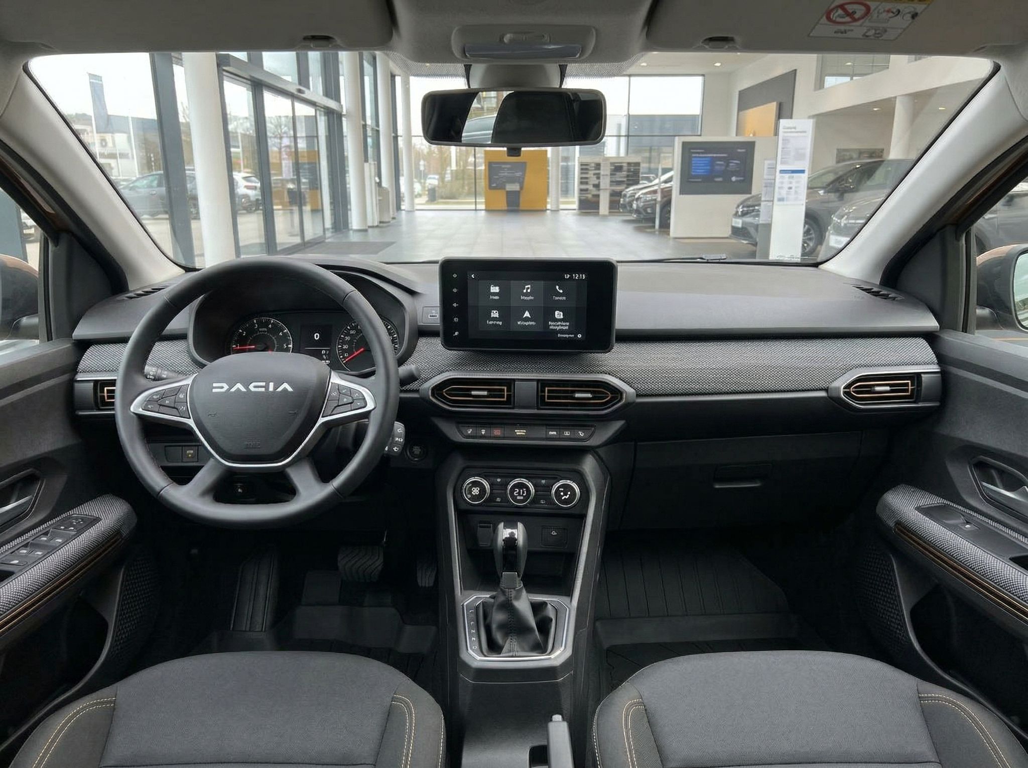 Dacia Innenraum mit schwarzem Armaturenbrett, Touchscreen und Panorama-Schiebedach im Autohaus